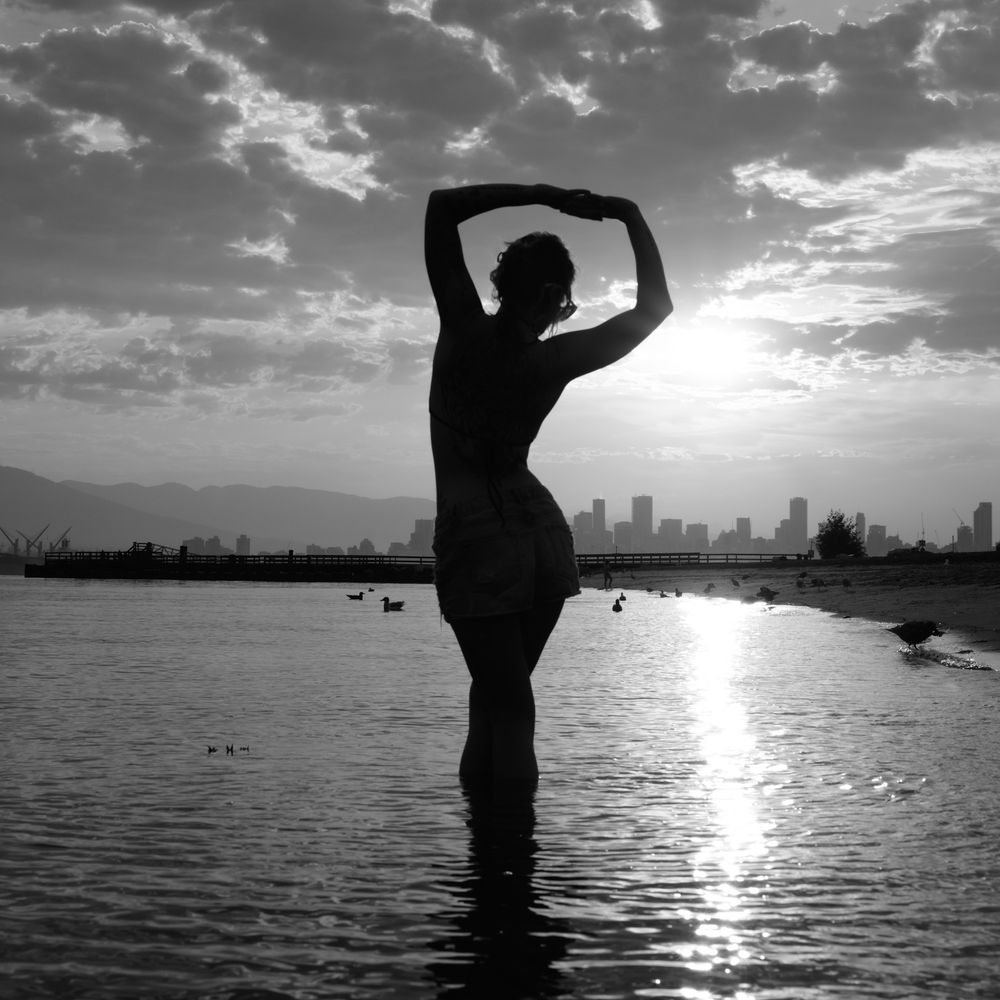 Black and white silhouette of woman at sunset waterfront, North Vancouver portrait photographer