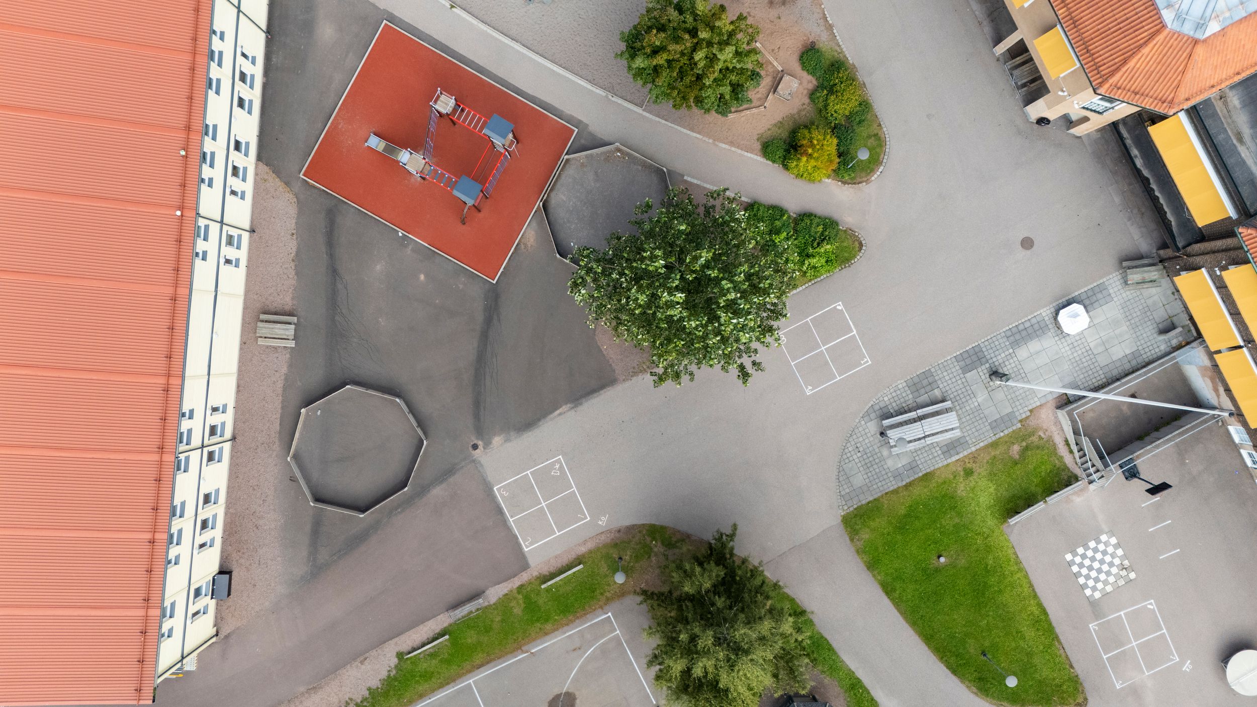 Aerial view of a parking lot with school buses and surrounding buildings.