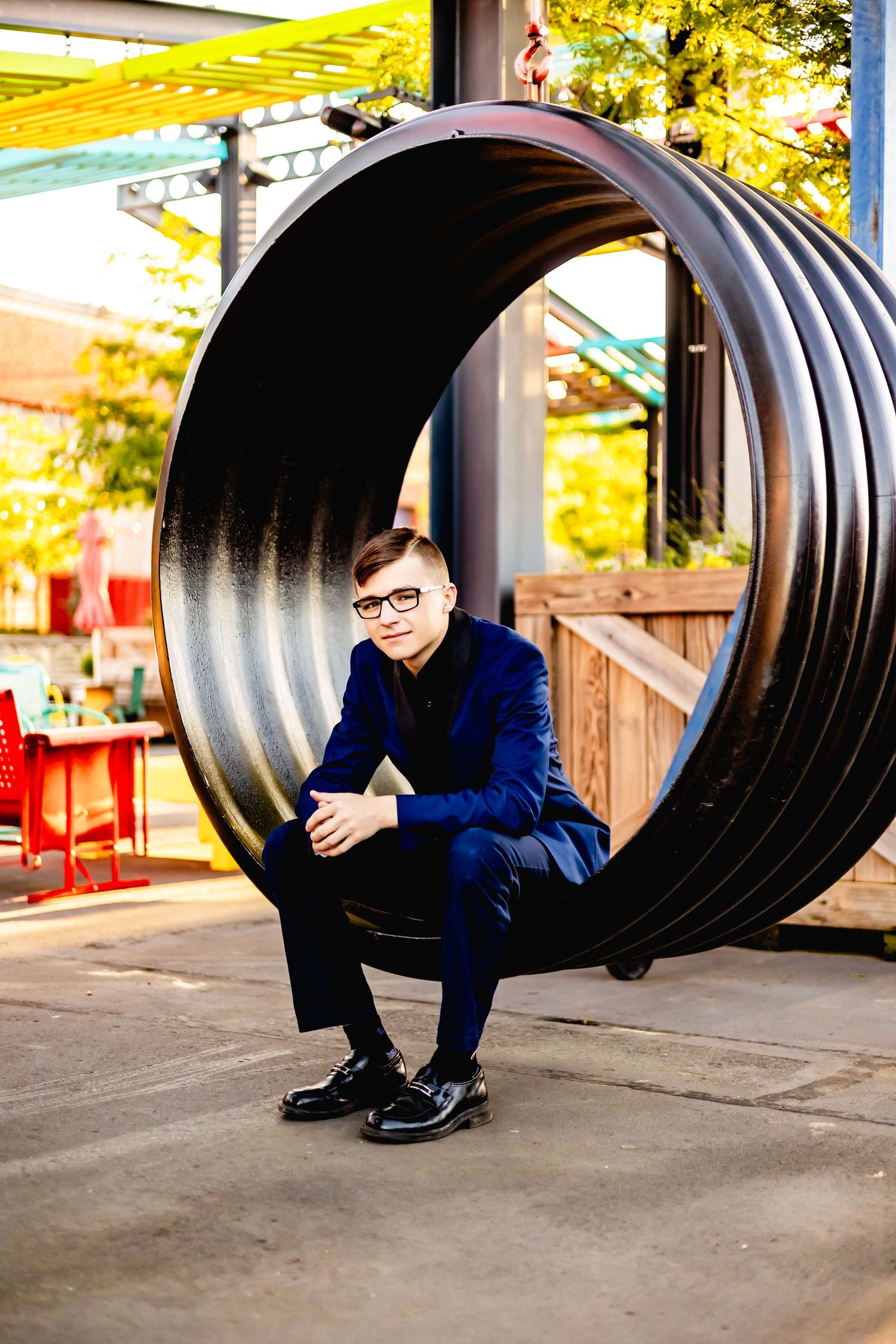 Person in blue suit sitting inside a large industrial pipe installation.