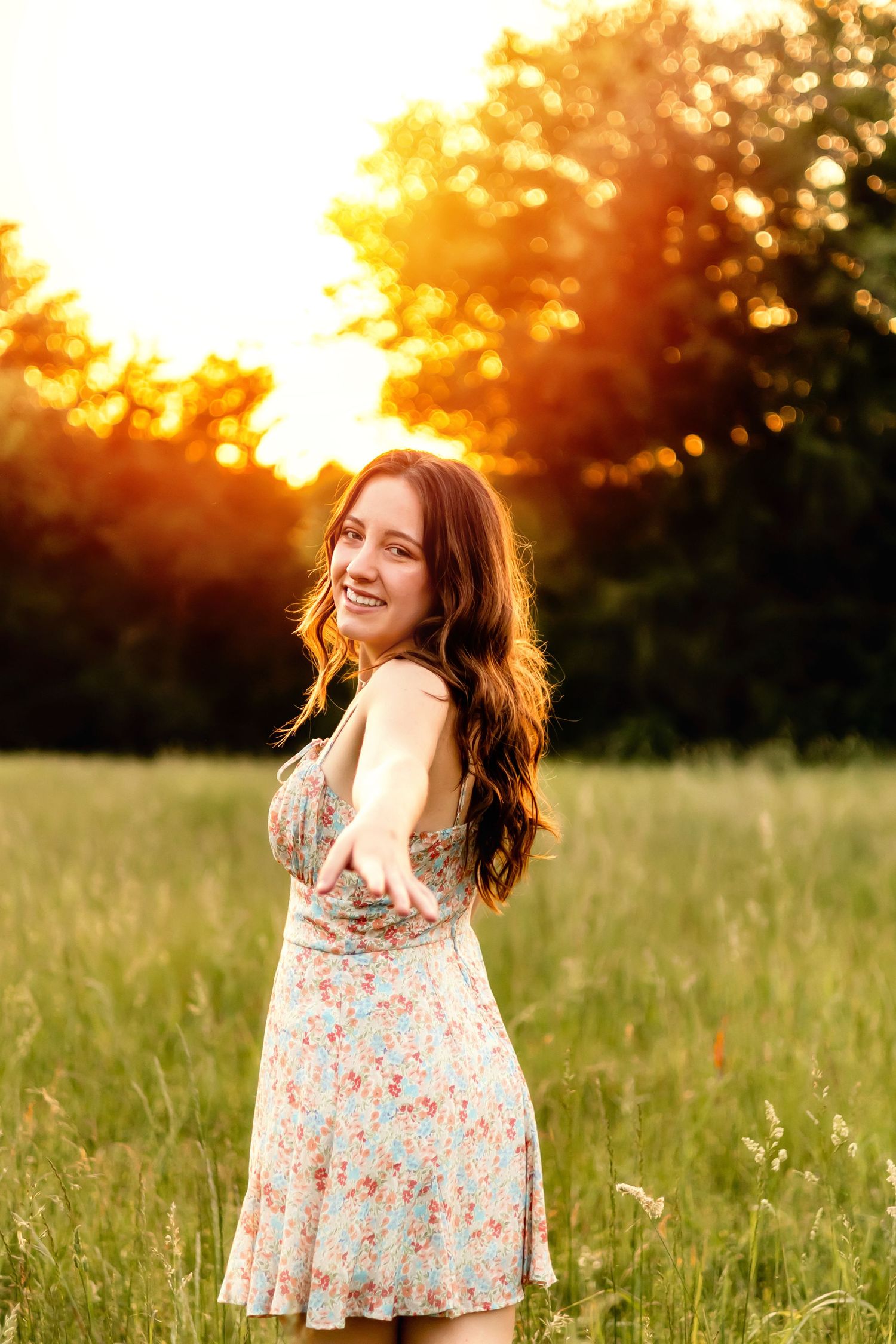 Person in floral dress twirling in golden sunset field.