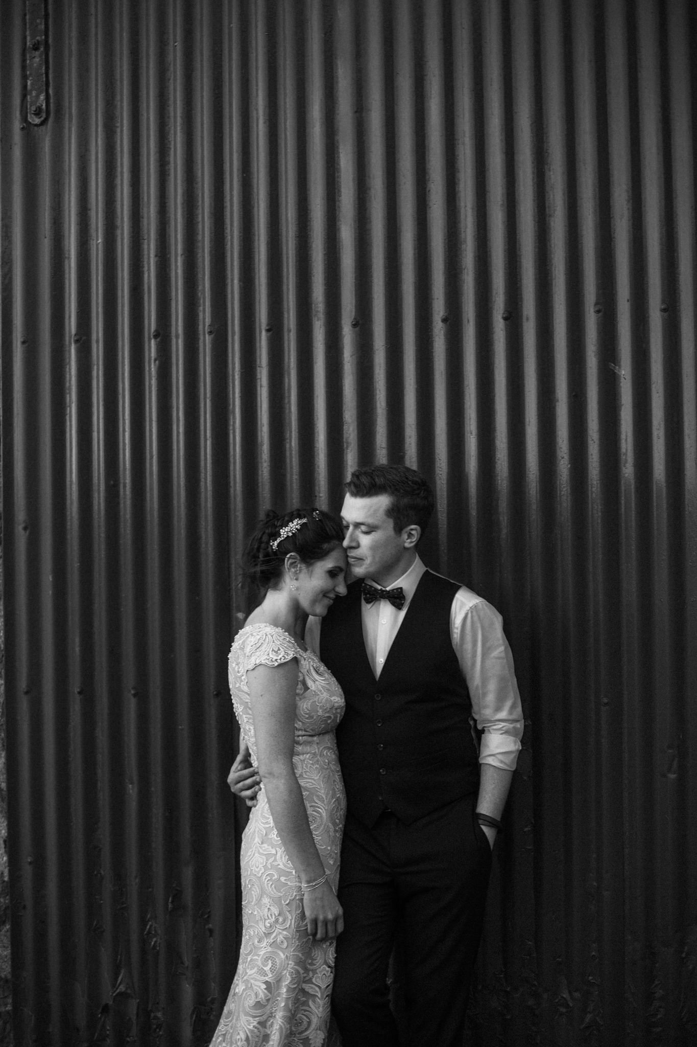 bride and groom casually embracing in front of an iron gate