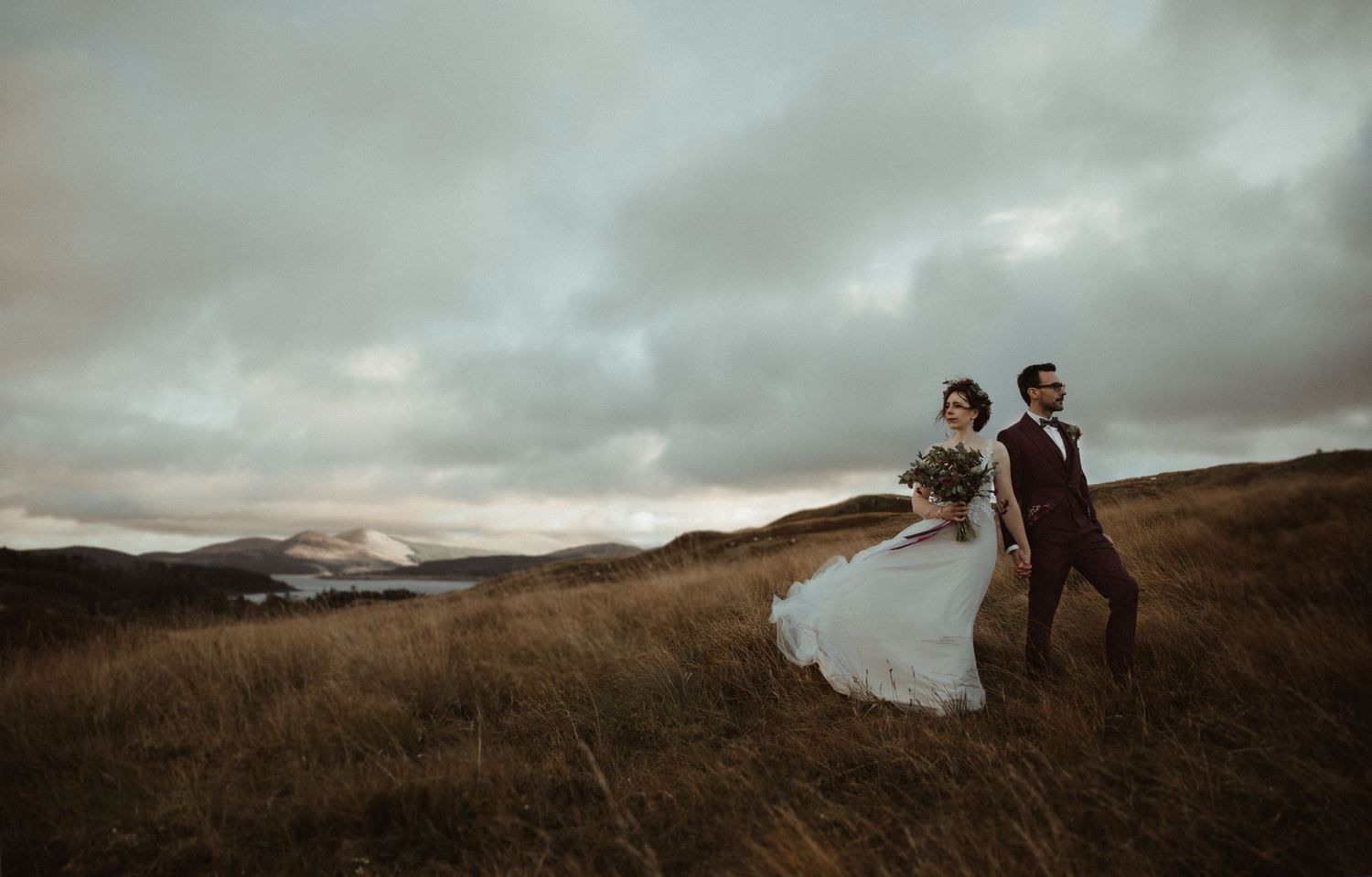 bride and groom posing on top of a mountain with scenic views in the background