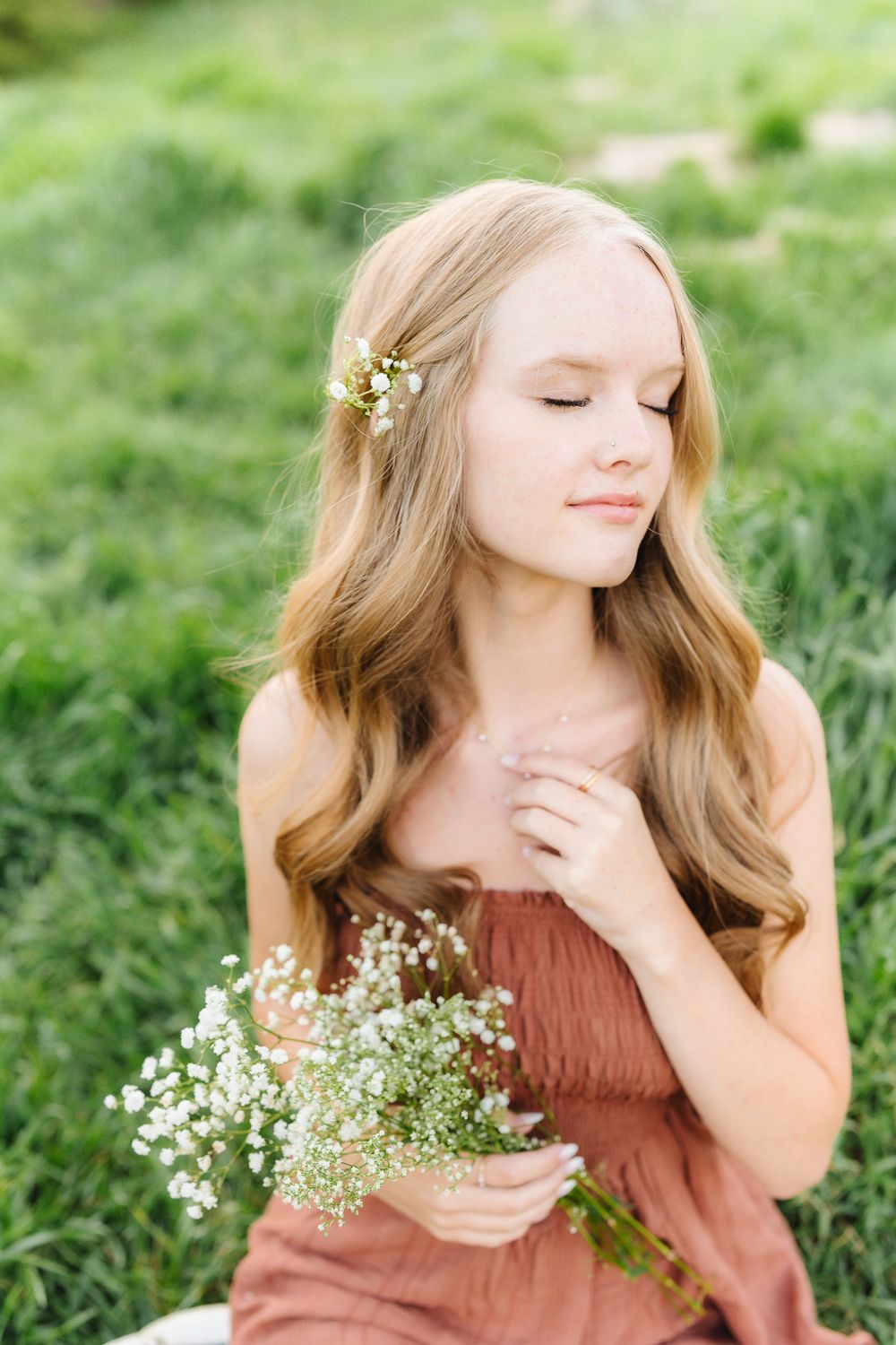Close-up portrait with baby's breath flowers against lush green background.