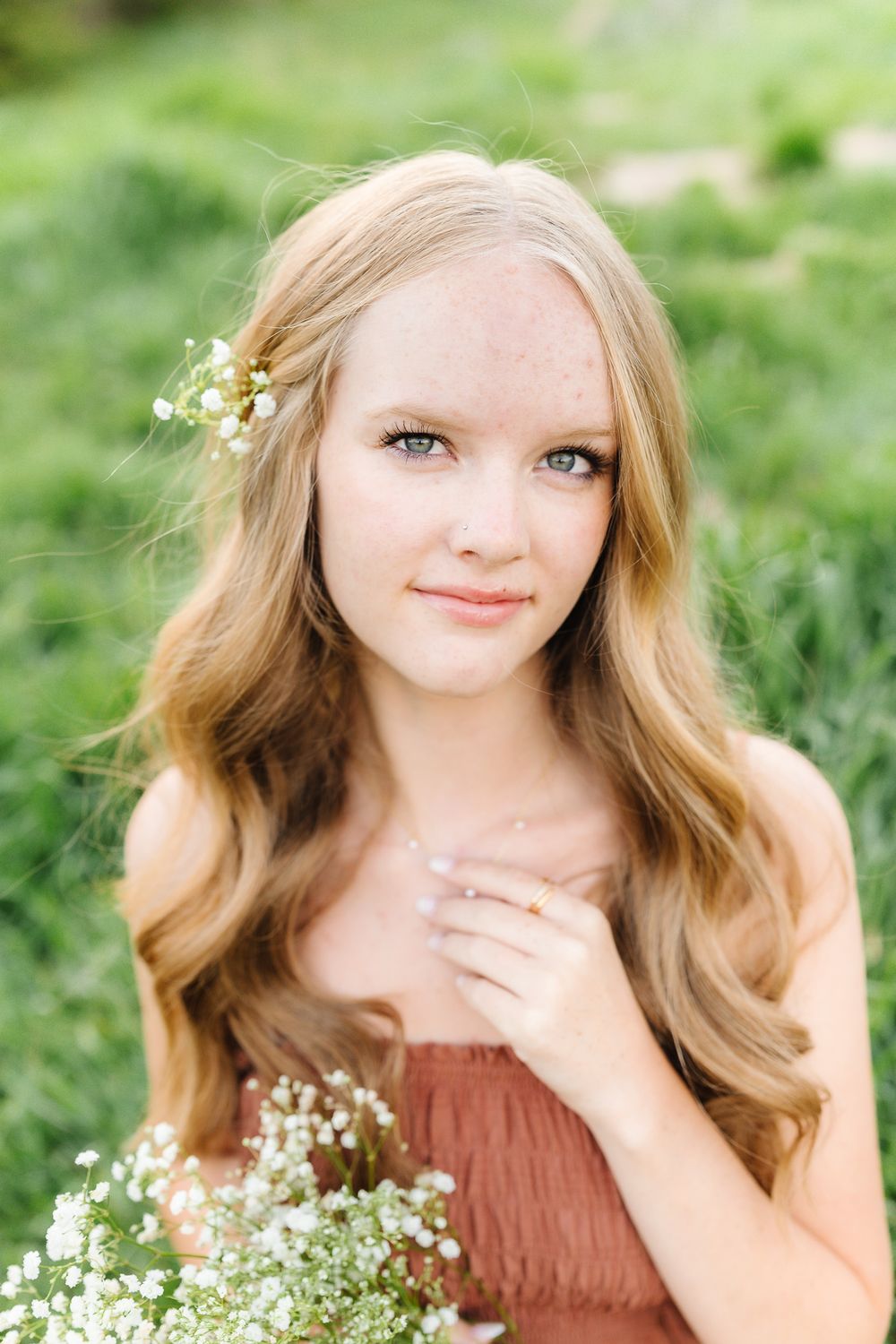 A rustic portrait session in a grassy field with delicate baby's breath flowers and a brown dress.