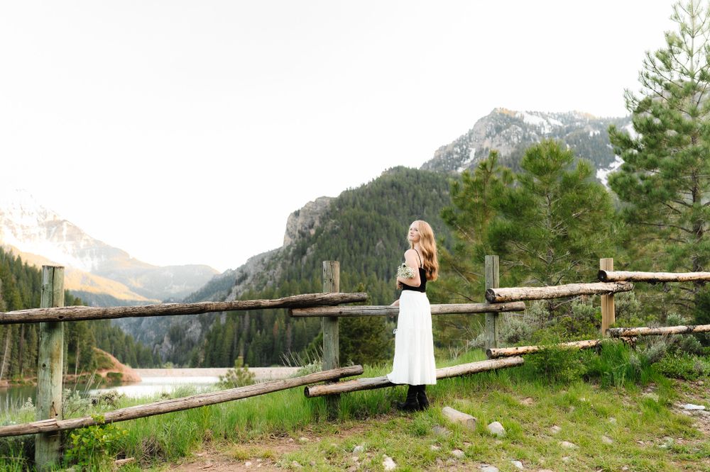 Mountain landscape with rustic wooden fence and scenic mountain peaks in the background.