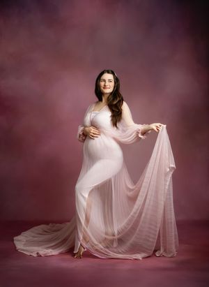 Ethereal maternity portrait series in soft pink tones showing flowing fabric movement against a dreamy burgundy backdrop.