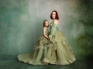 Enchanting portrait of matching sage green ballgowns in a dreamy studio setting.