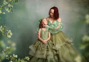 Artistic portrait with matching sage green dresses amidst delicate foliage and soft lighting.