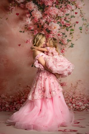 Dreamy pink photography setup featuring flowing tulle dresses and scattered rose petals in a romantic setting.