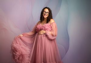 A dreamy photoshoot featuring a flowing pink tulle gown in multiple romantic poses against a soft background.