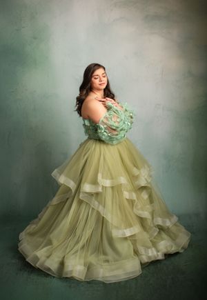 Elegant ball gown in mint green and gold tulle with dramatic ruffled layers.