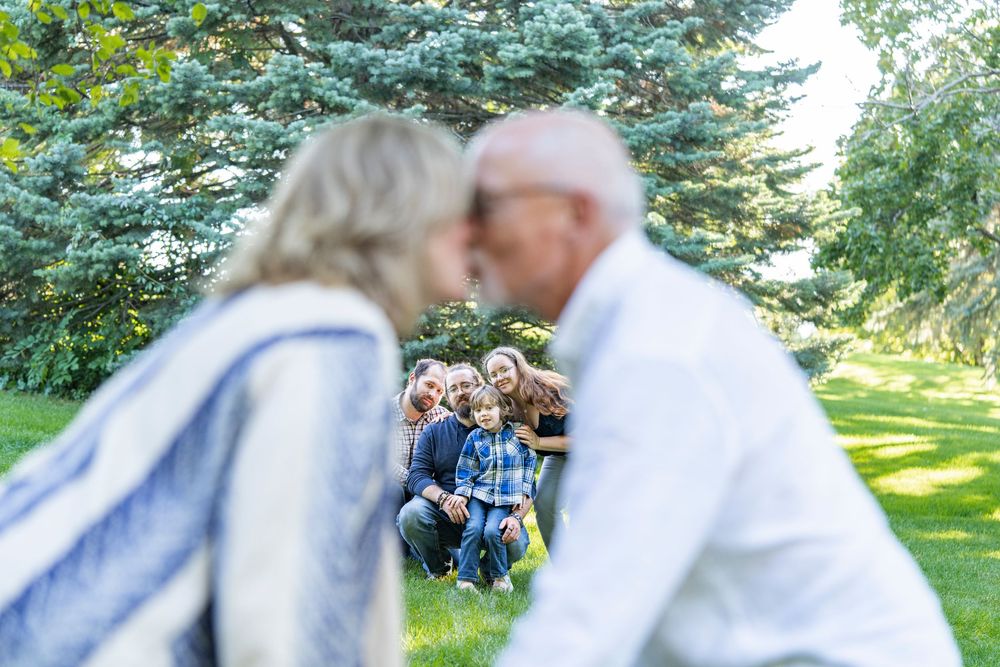 An older couple in the foreground with a group of family members posing in the background.