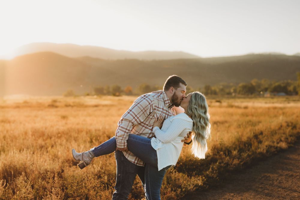A romantic golden hour moment between two people in a sunlit field at sunset.