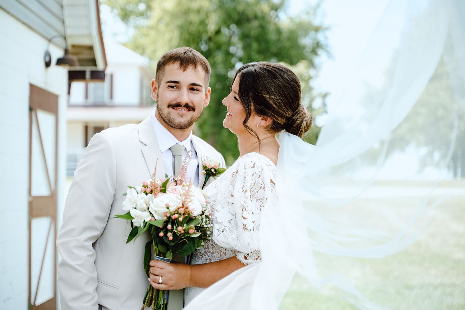 A romantic moment between newlyweds in front of a white stone church with gothic architecture.