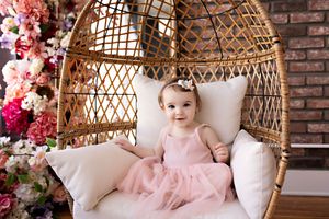 Vintage style nursery with bamboo hanging chair, pink floral decorations and exposed brick wall backdrop.  Kendall Kuss Photography