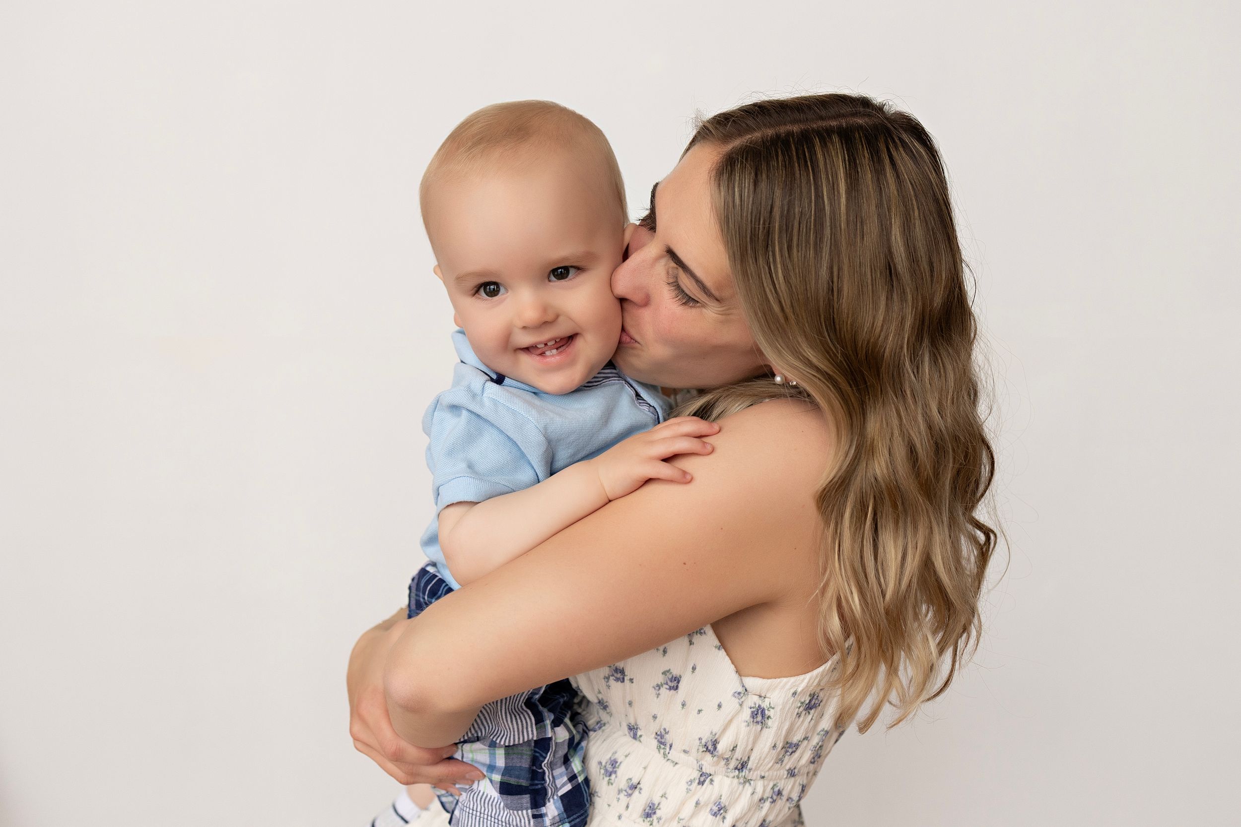 A tender moment captured between parent and baby in soft, natural light against a light backdrop.  Kendall Kuss Photography Watertown WI
