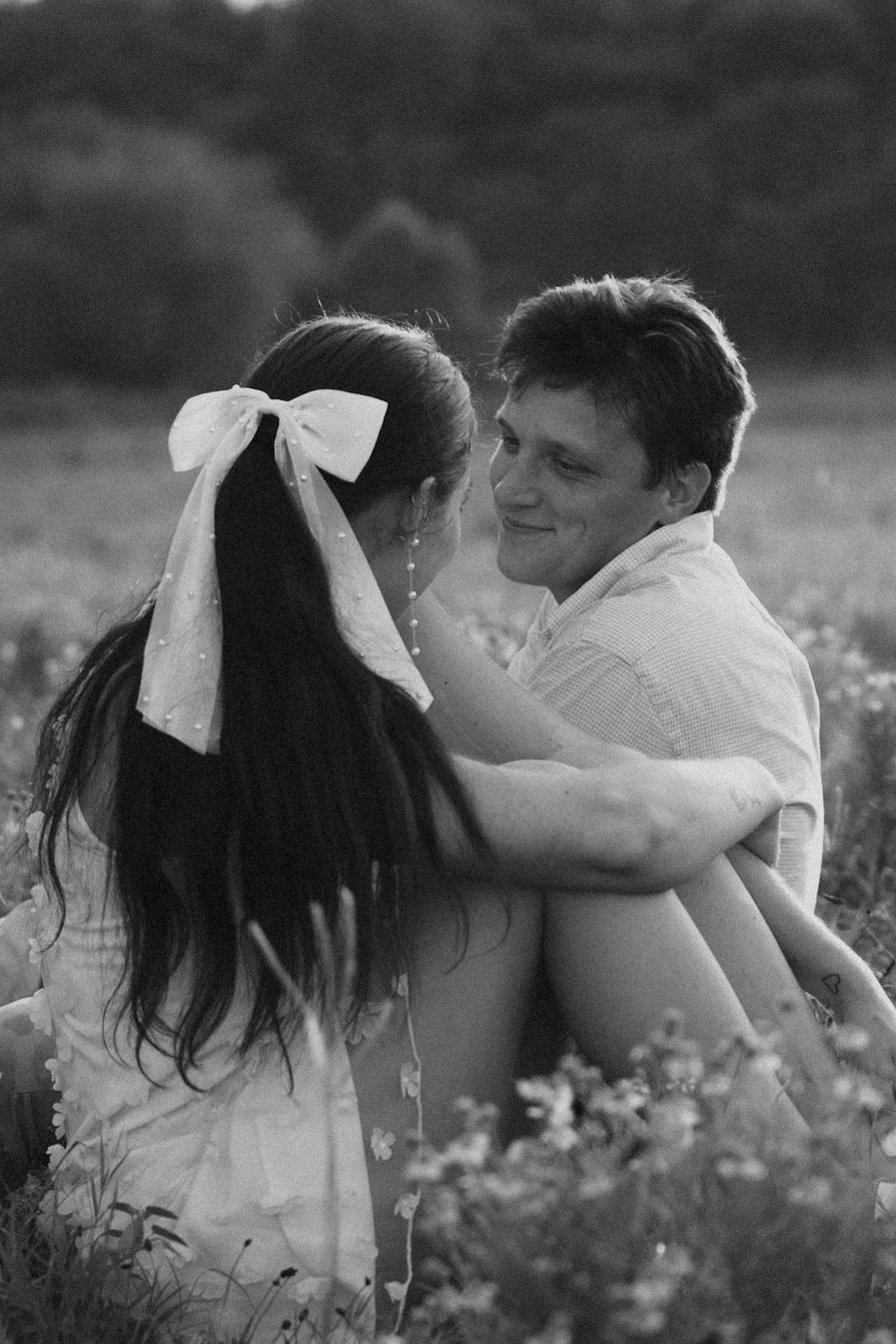 A tender black and white romantic moment shared between two people embracing in a wildflower meadow.