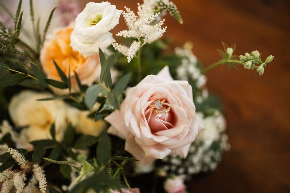Delicate pink and peach roses arranged with white baby's breath flowers against a dark wooden background.