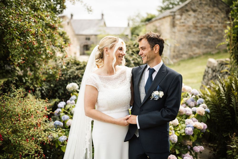 A couple shares intimate moments in a garden setting during their wedding celebration.