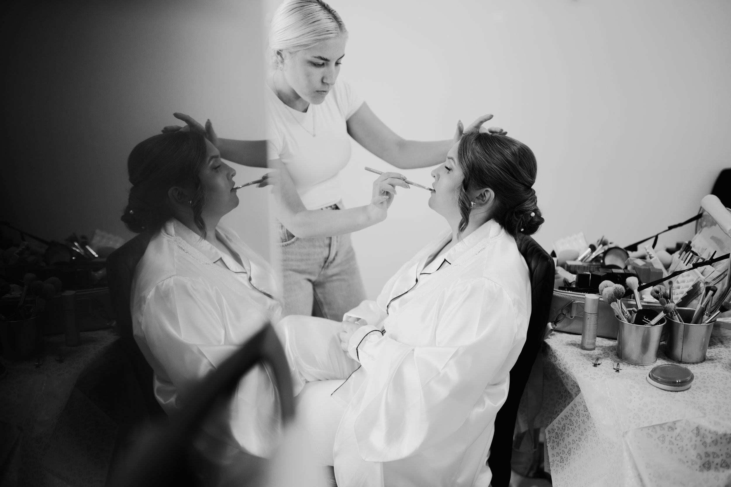 Black and white photo of wedding preparations with three people helping each other get ready in white attire.