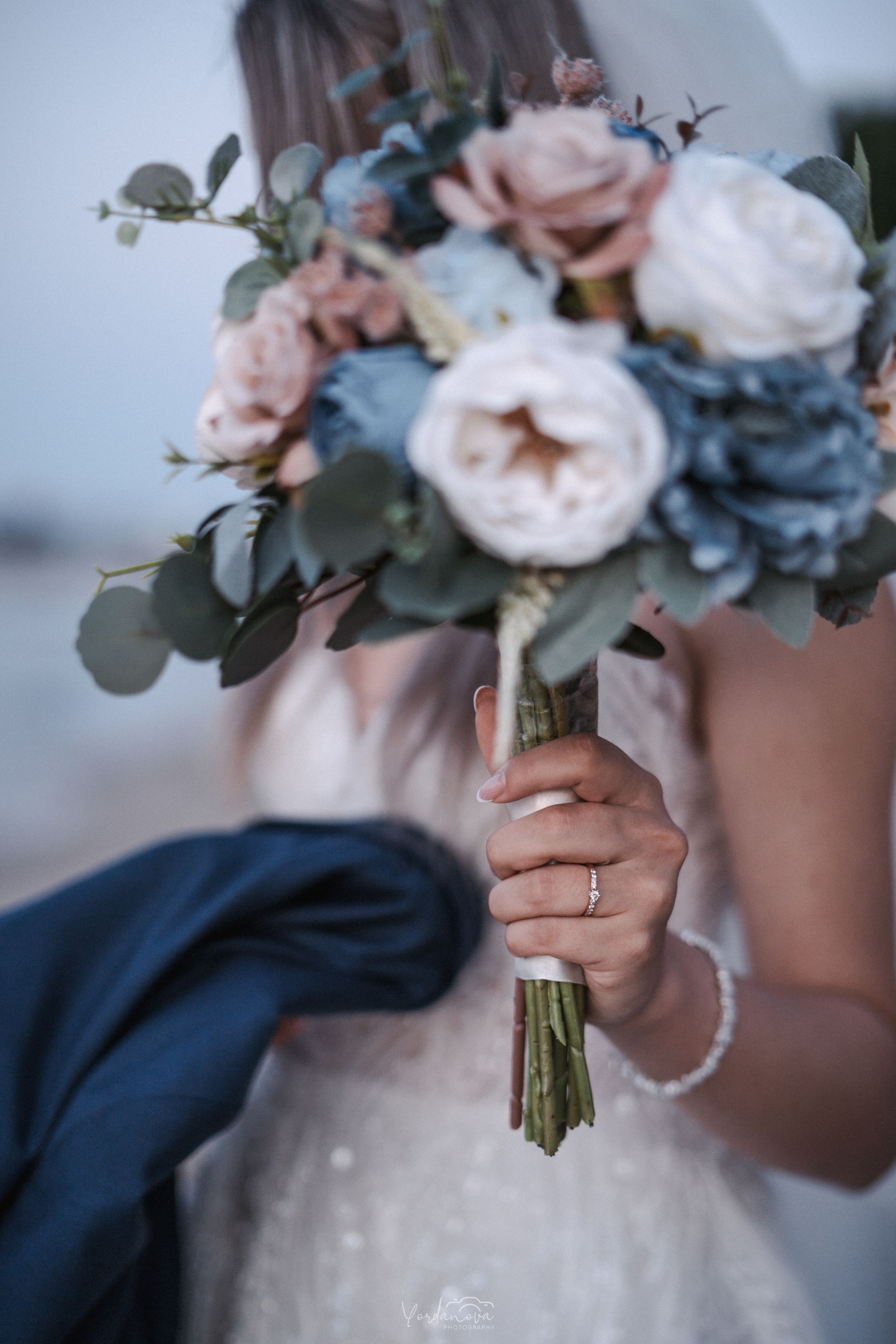 Wedding bouquet with pink and blue roses tied with white ribbon.