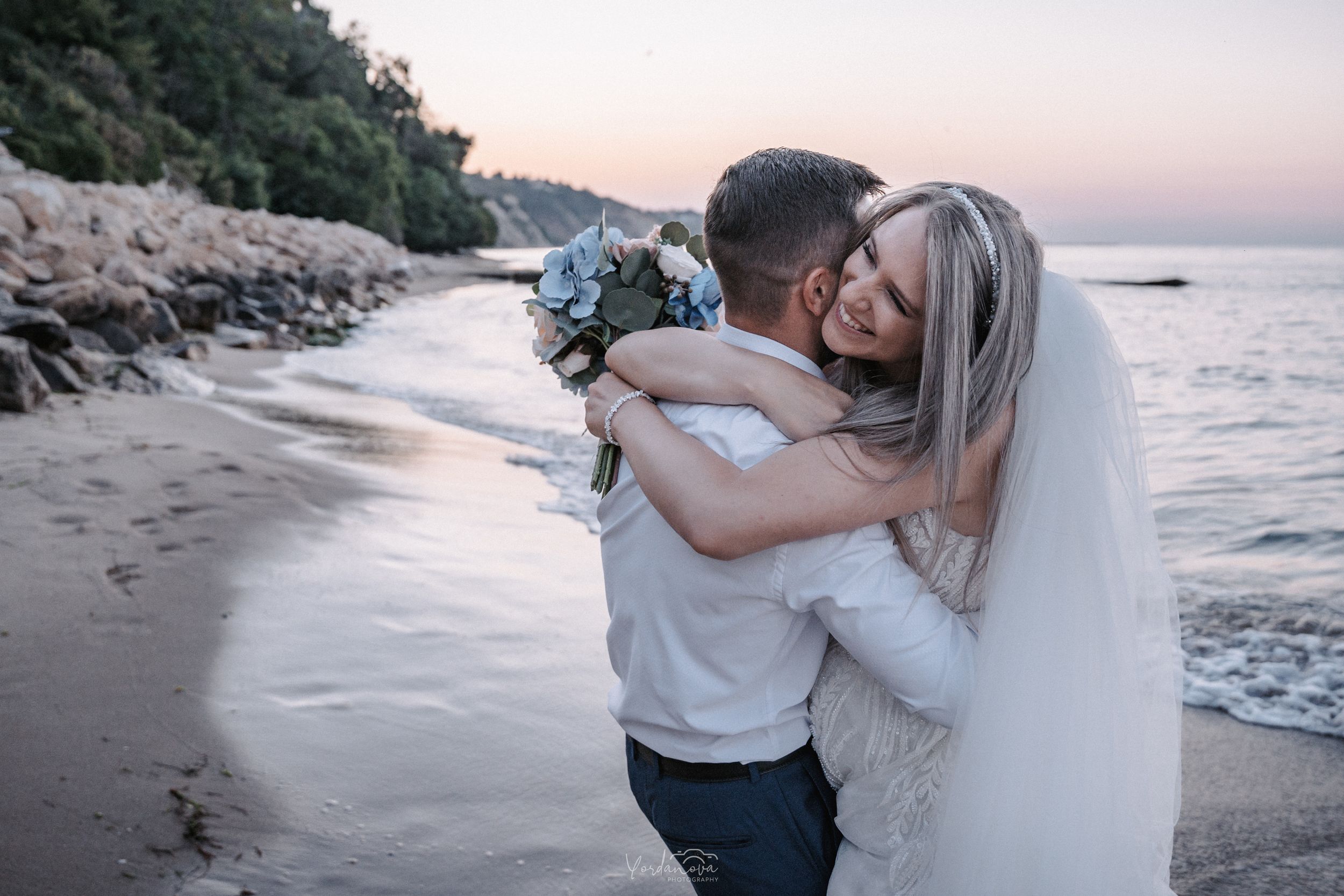 A couple poses against the ocean backdrop during golden hour.