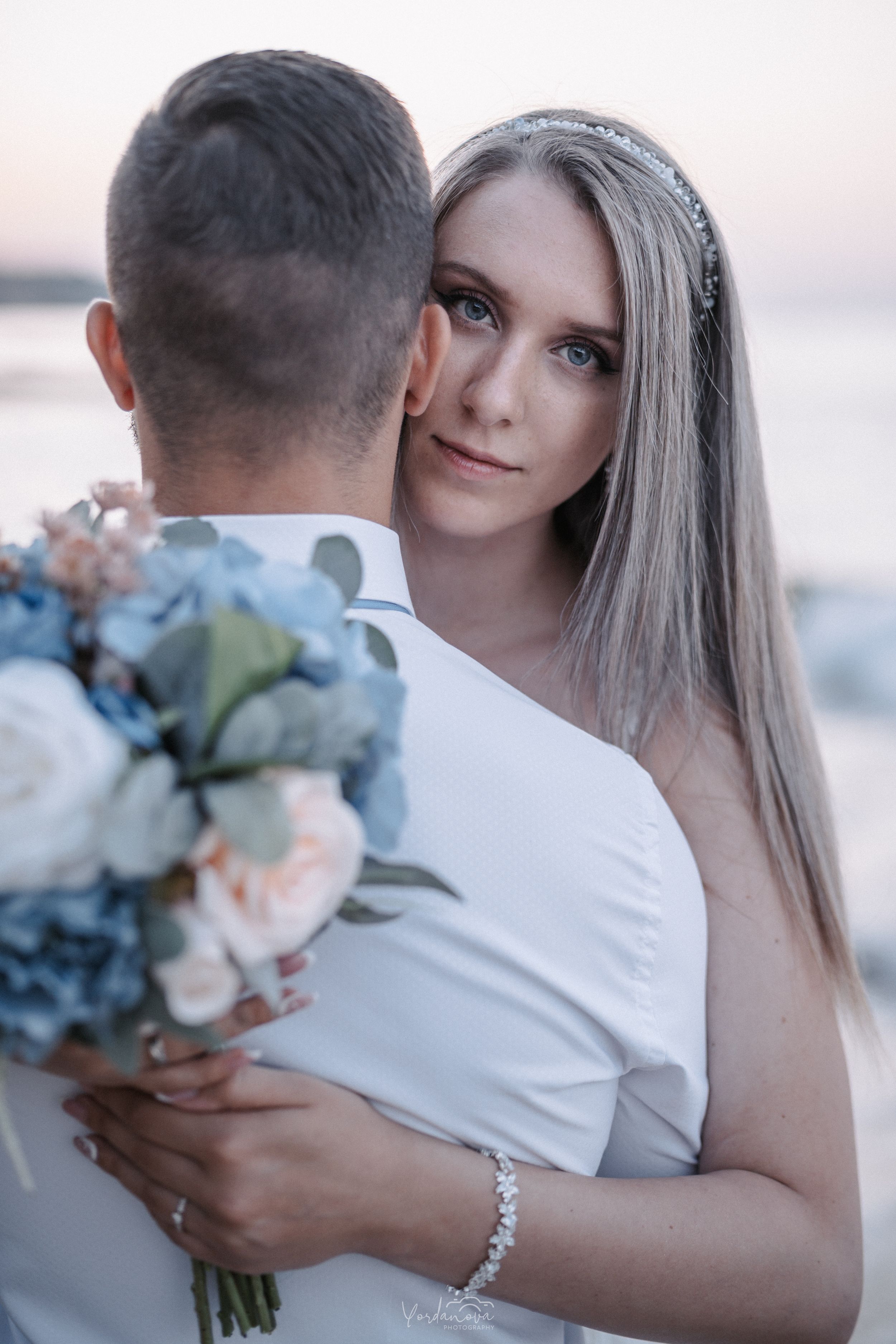 A romantic embrace captured with soft pastel skies and delicate flowers.