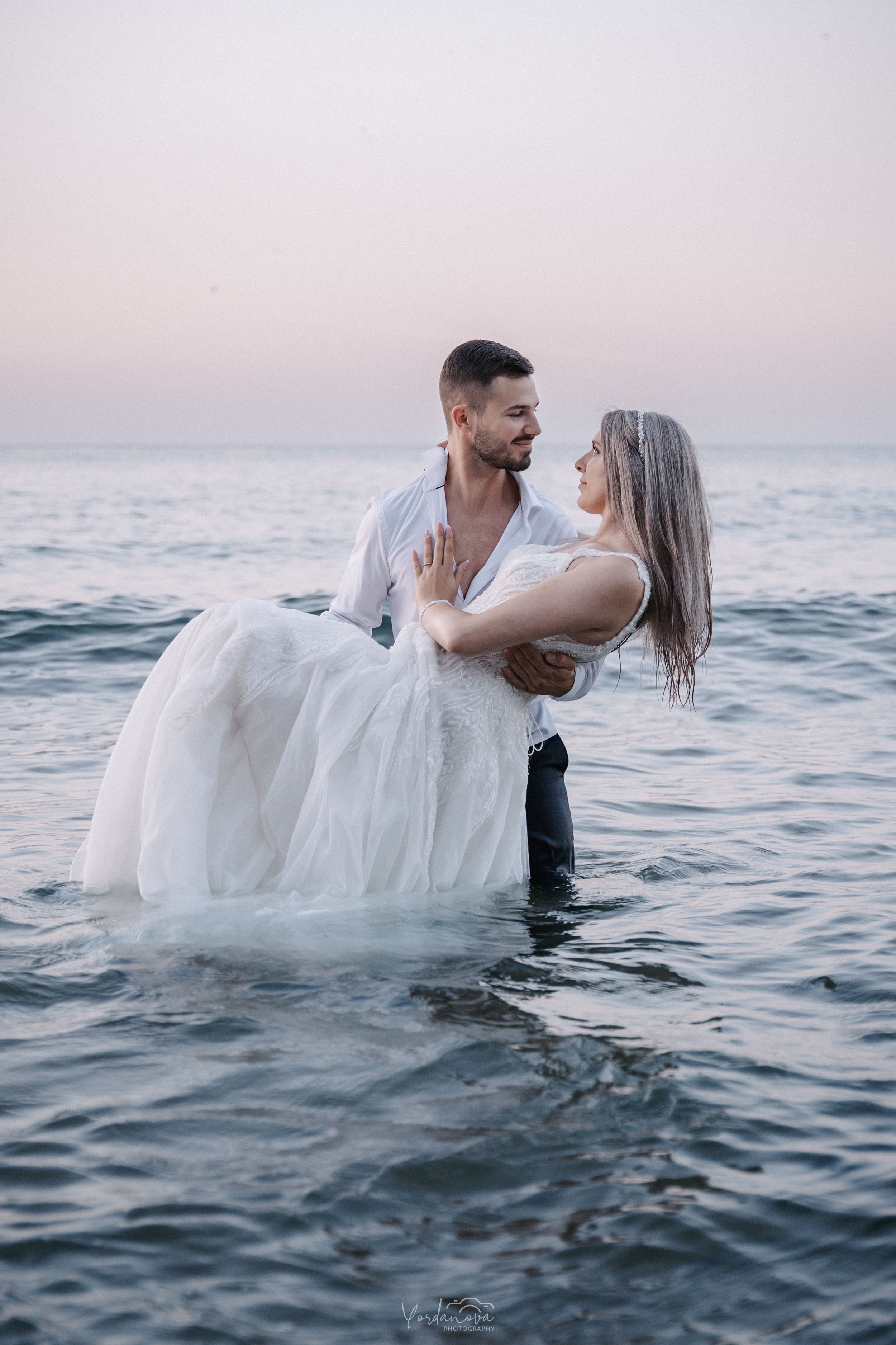 A dreamy ocean photoshoot with flowing white fabric floating on water.