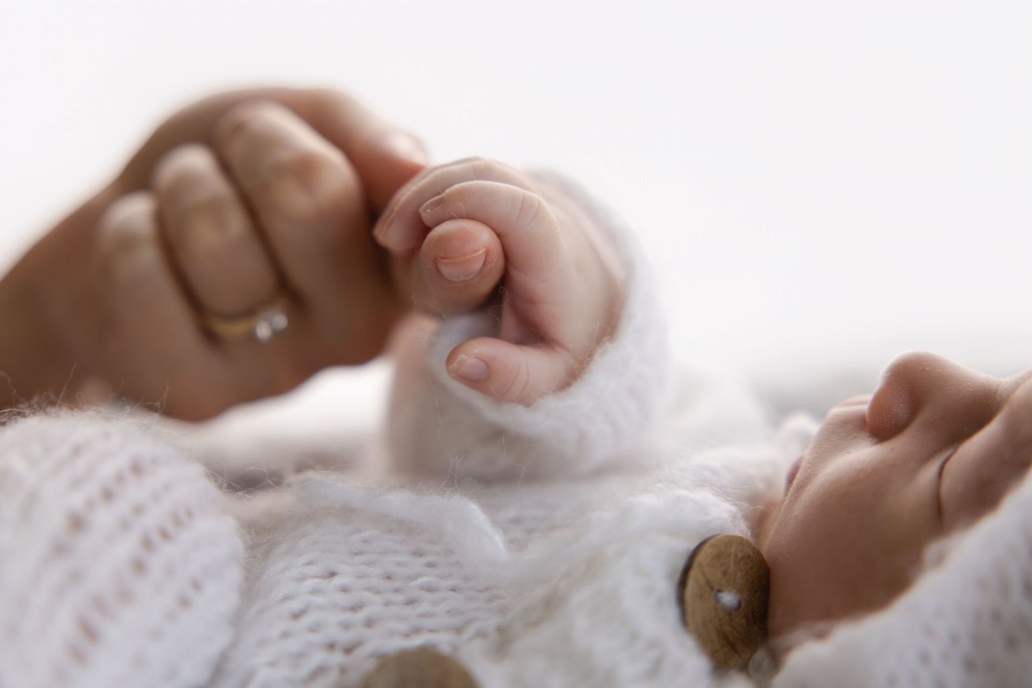 Salt Lake Newborn Photographer - Two caring hands gently holding a baby's tiny feet in a tender, intimate moment.