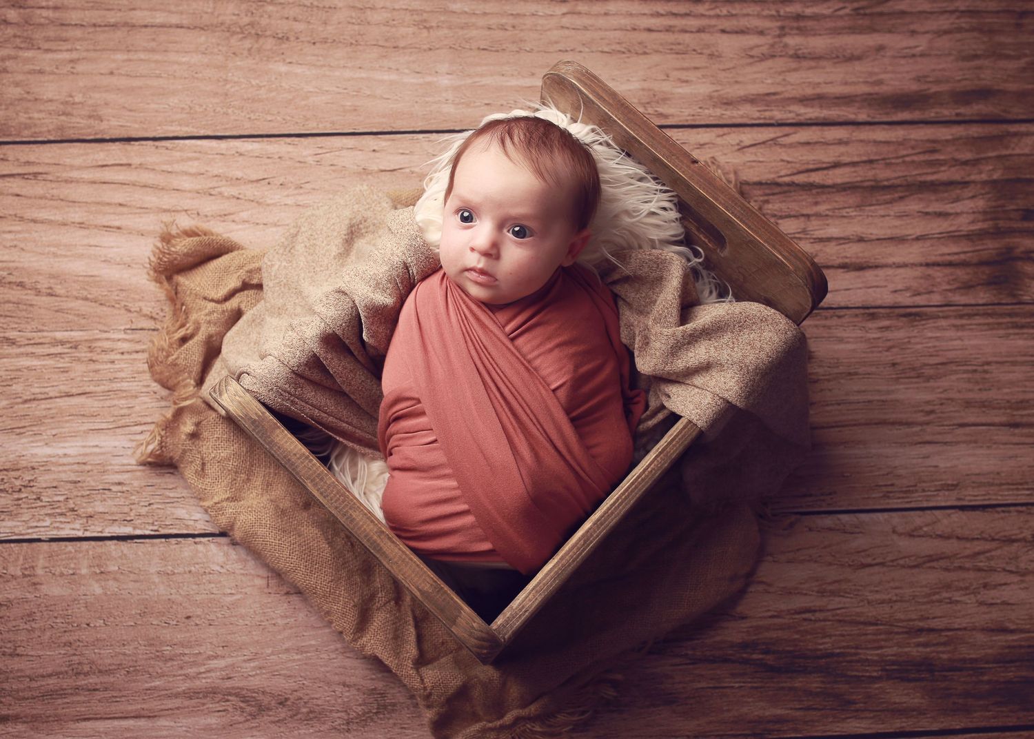A peaceful newborn baby girl wrapped in soft fabrics, captured in a serene and intimate setting, showcasing the delicate beauty in photo