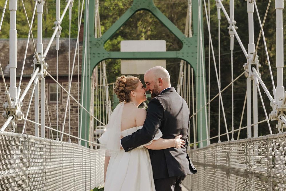 Couple embracing on a suspension bridge during their wedding day.