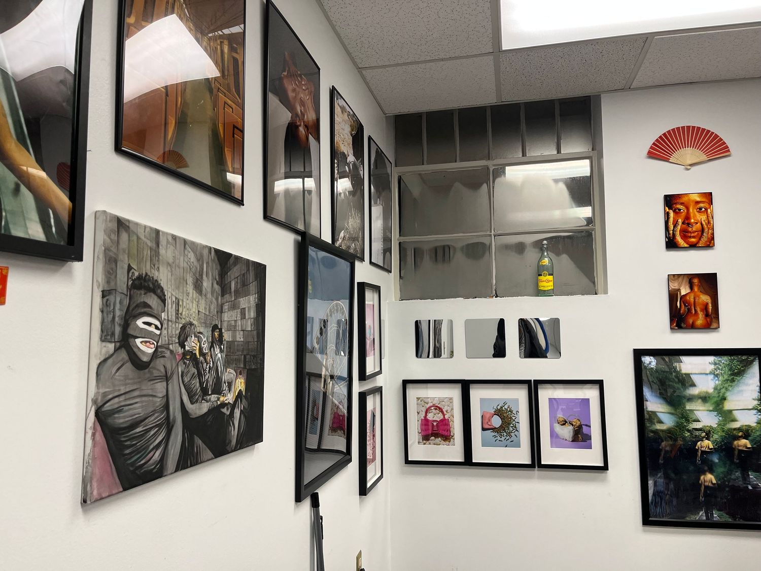 A gallery wall displaying black and white photographs and artwork with Asian decorative elements.