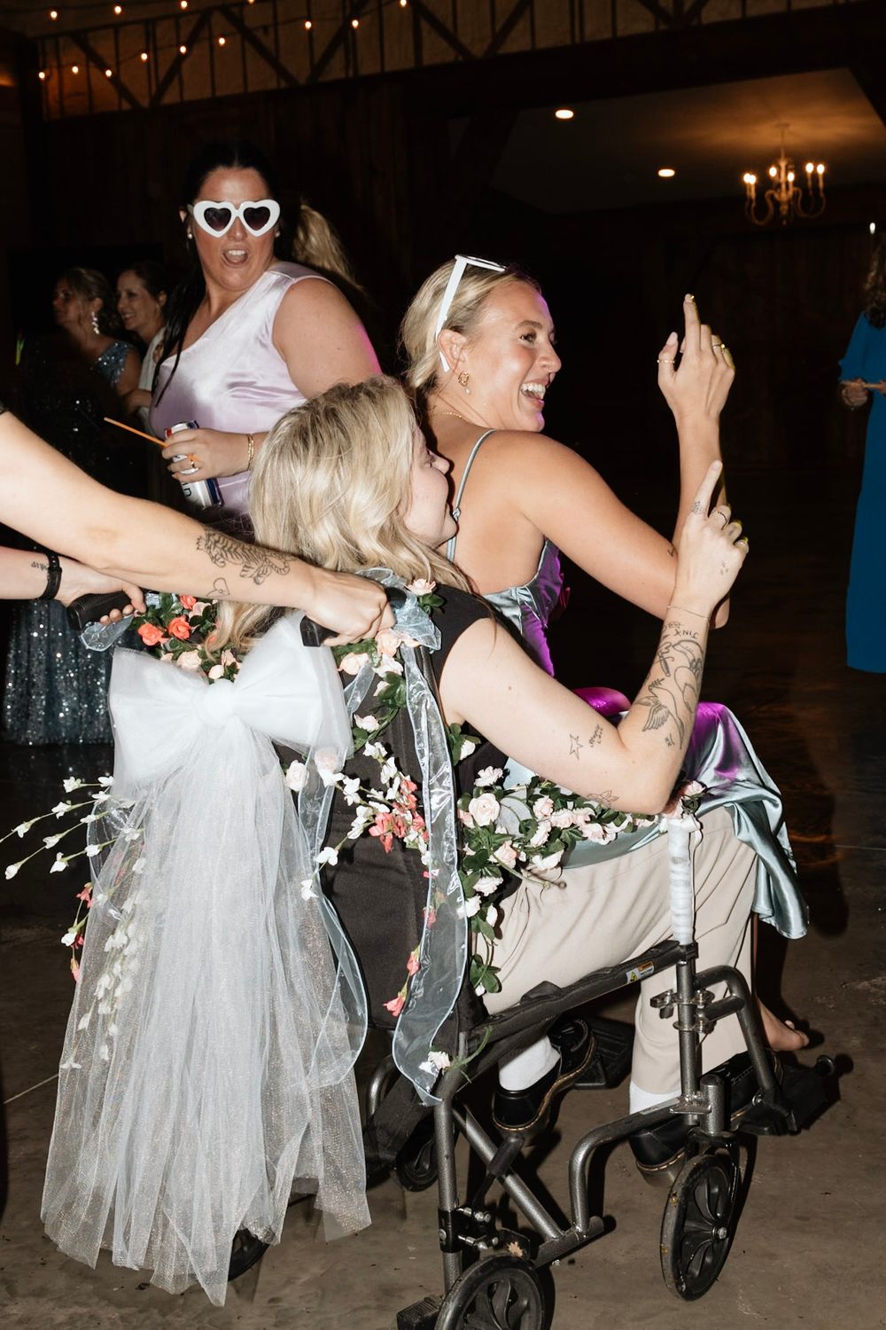 Joyful wedding party guests, including one in a wheelchair, dancing and celebrating on the dance floor.