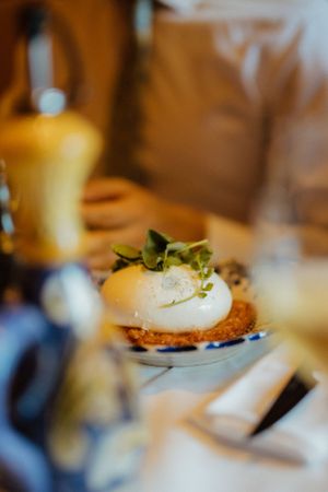 A gourmet poached egg sits atop a crispy base garnished with fresh microgreens in warm lighting.
