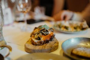 A gourmet burger topped with melted cheese and mushrooms served on a rustic wooden board in an upscale restaurant setting.