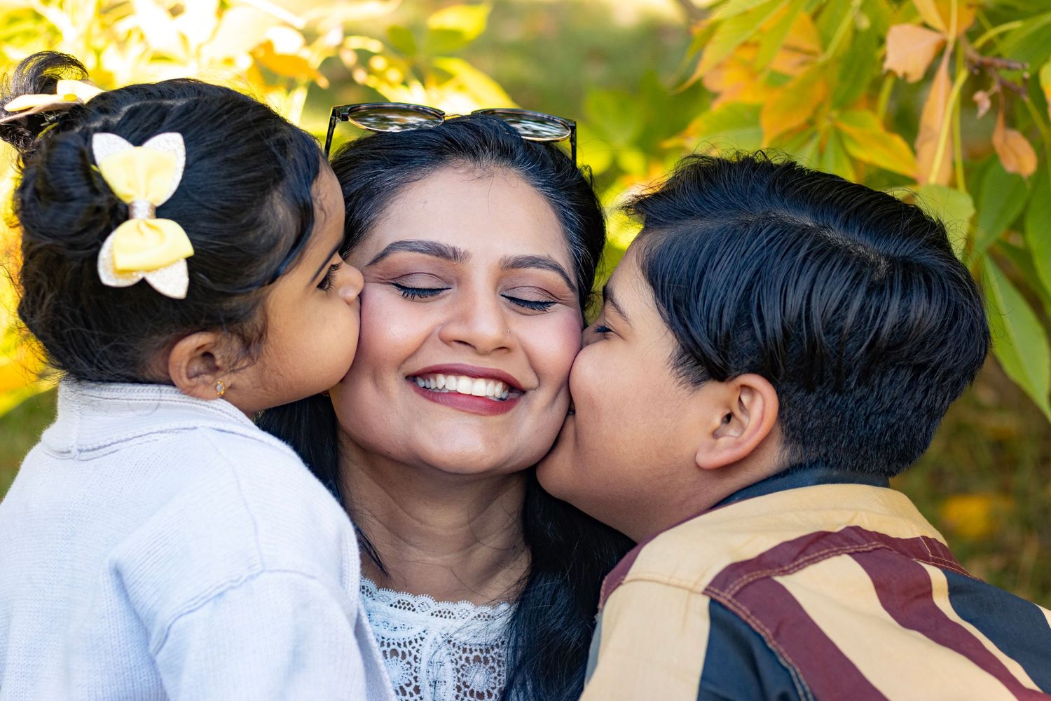 Kids kissing their mom on her cheeks