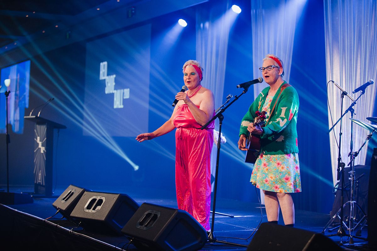 entertainers on stage singing at a charity fundraiser event