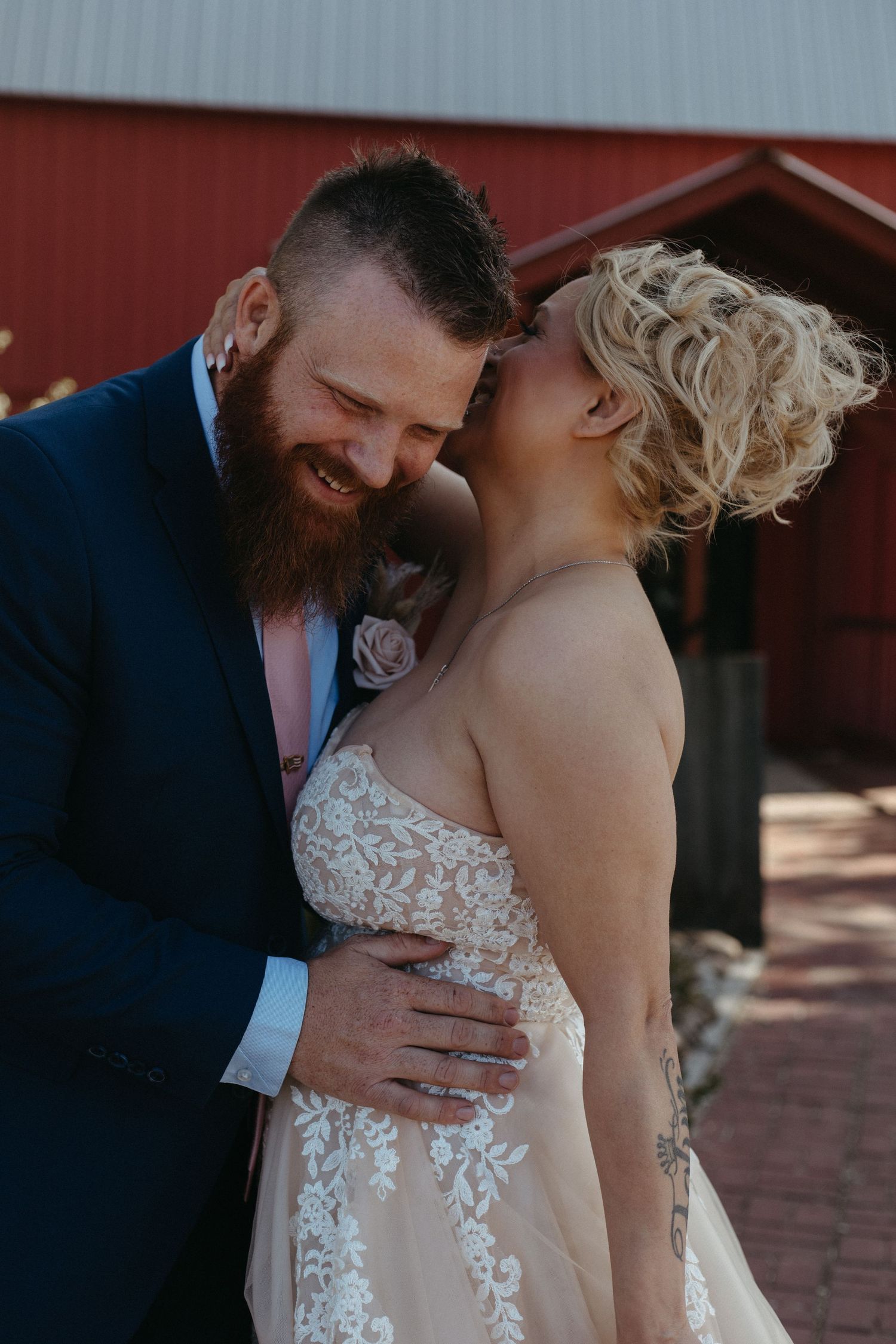 A romantic moment between newlyweds in front of a red barn.