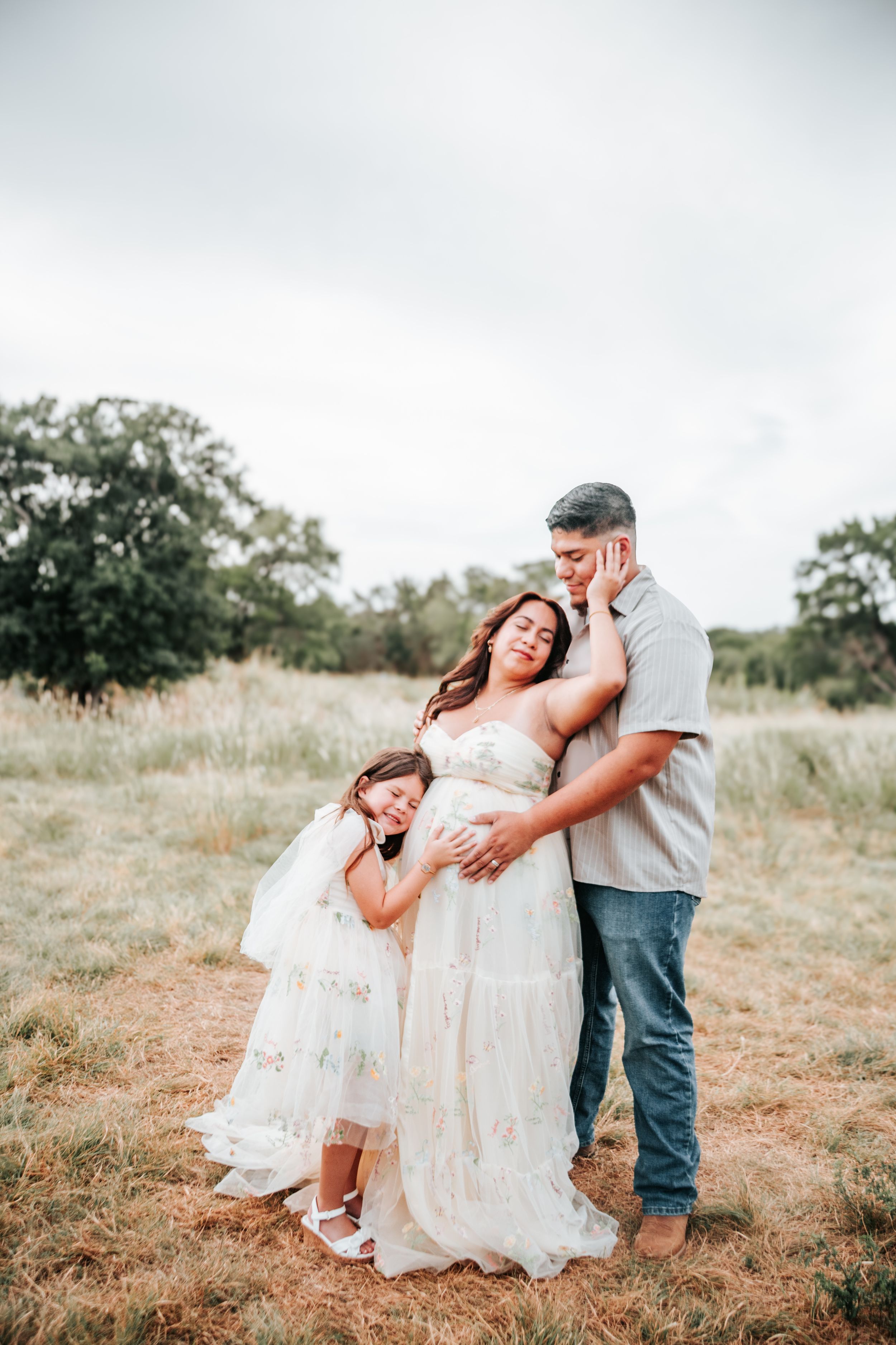Four romantic soft-focus photos showing a couple in white embracing in a rustic outdoor field setting during sunset.