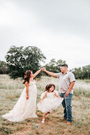 A couple in a field twirls playfully together with the bride's dress catching the breeze in a romantic outdoor moment.