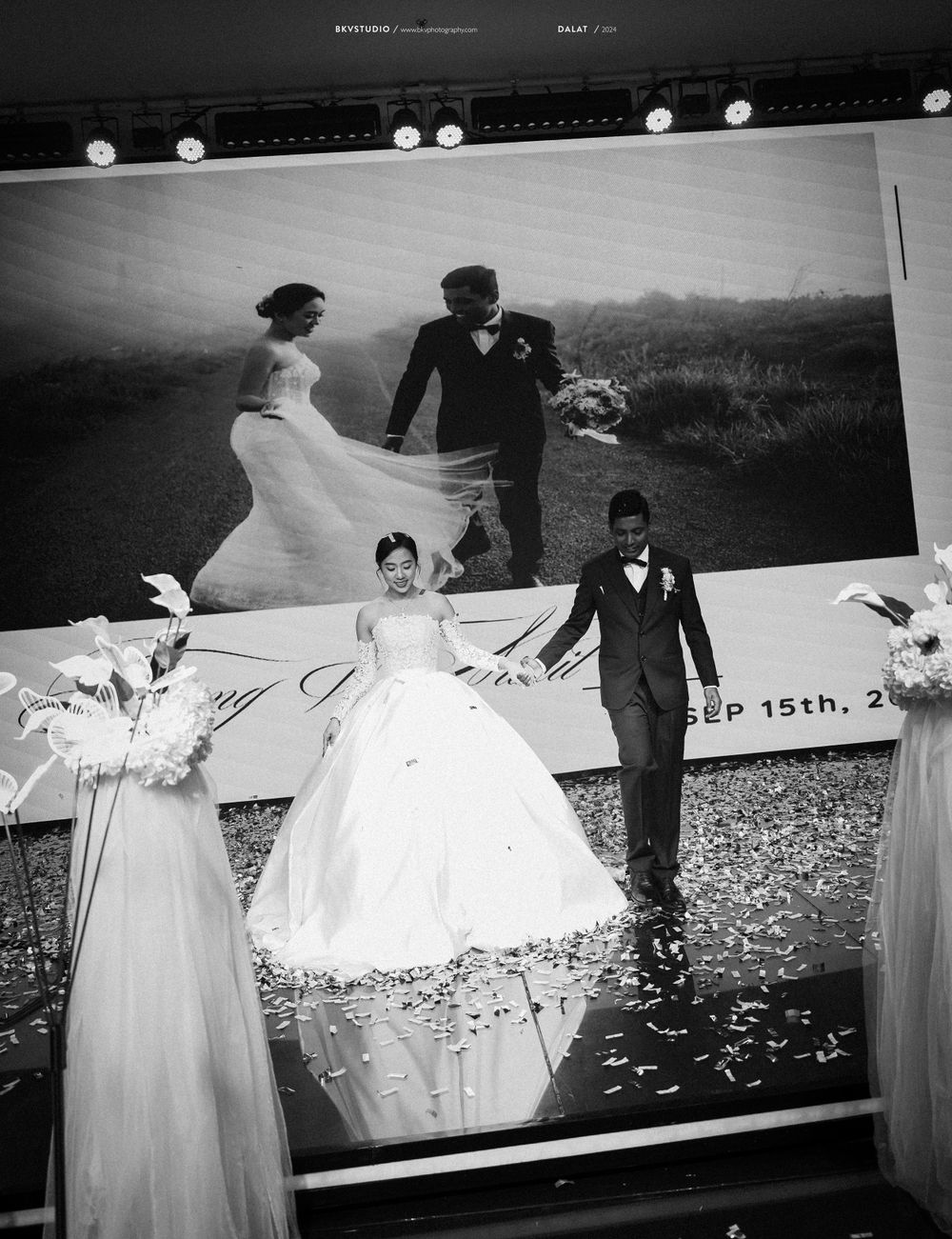Black and white wedding photograph displayed at reception with flower arrangements.