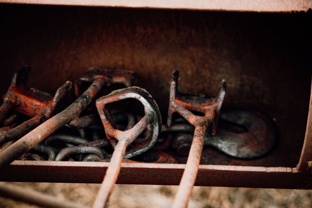 Rusty vintage farm tools and hooks stored in an old metal box on a ranch.