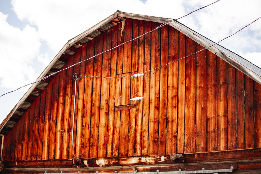 Rustic red wooden barn exterior with weathered vertical planks under a cloudy sky.