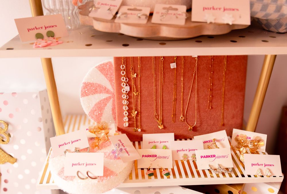 Display of pink jewelry and accessories arranged on wooden surfaces in retail setting.