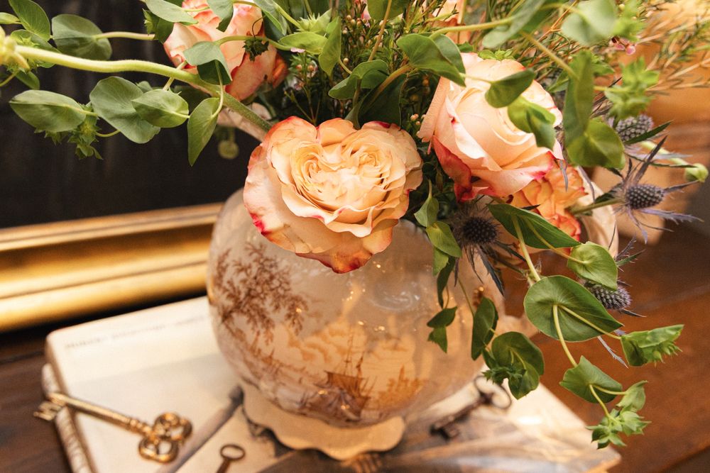 Close-up of peach-colored roses with green foliage arranged on a wooden surface.