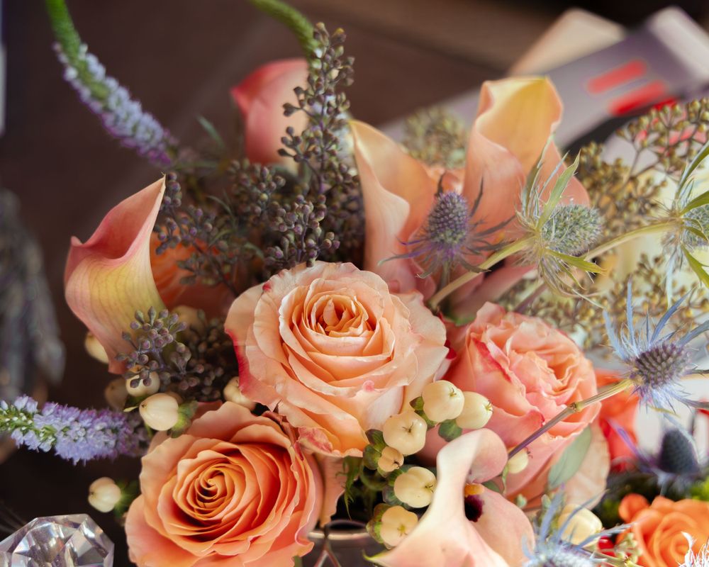 Peachy pink roses arranged with mixed florals and delicate foliage in an elegant display.