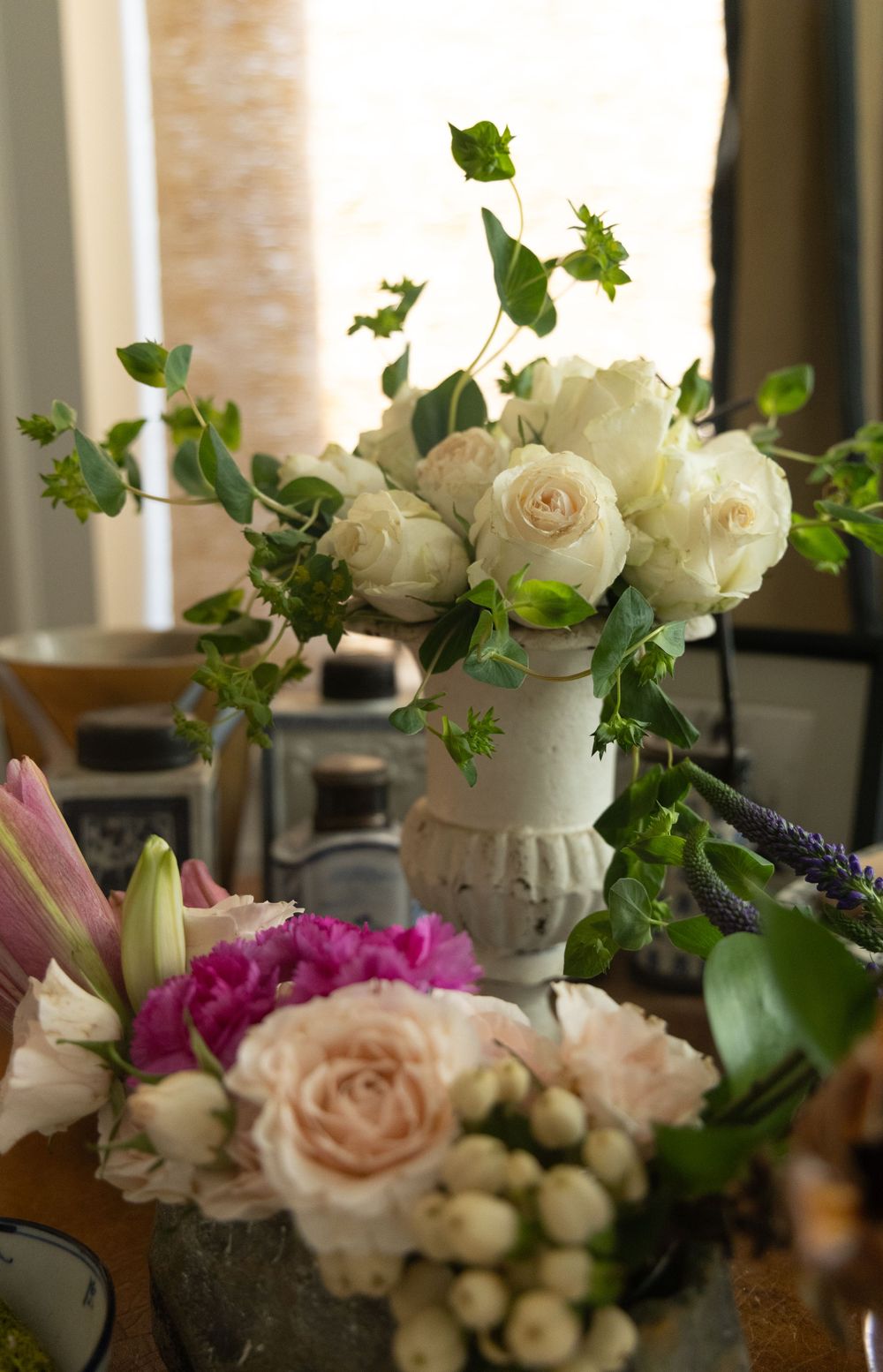 Elegant floral arrangement featuring white and pink roses with trailing ivy in natural lighting.