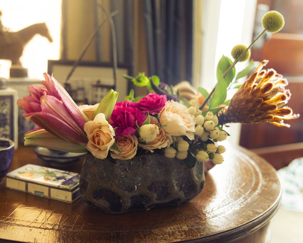 Floral centerpiece featuring peachy roses and greenery on a wooden table.