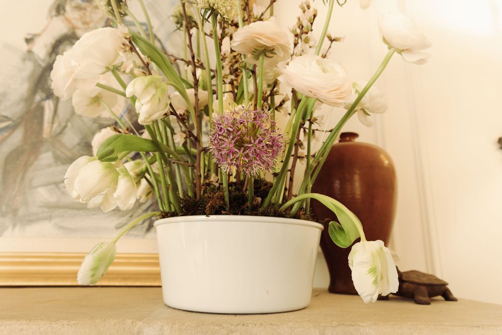 Delicate floral arrangements in white vases with pink and white blooms against a neutral background.