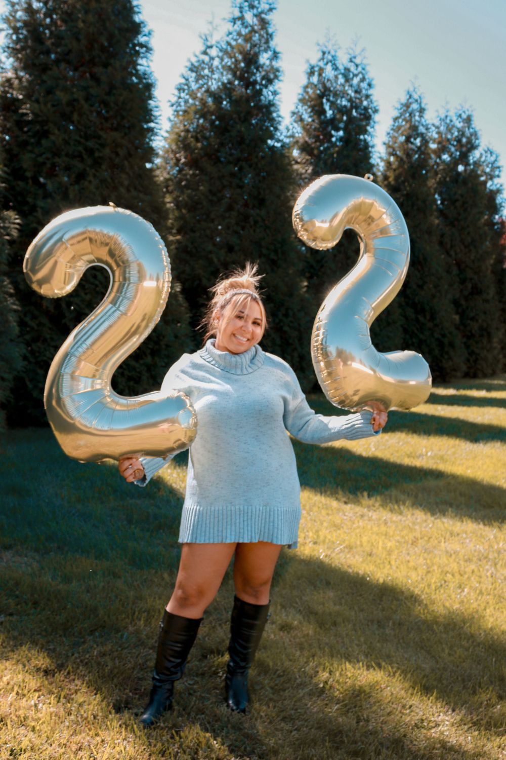 Person celebrating 22nd birthday outdoors with large silver number balloons.